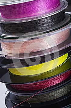 Many reels with fishing line and braided fishing line in different colors