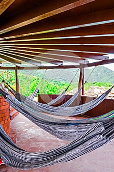 Many relaxing hammocks under a bungalow, with a blurred nature background in Tairona National Park, Colombia photo