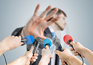 Many reporters are recording with microphones a politician who shows no comment gesture photo