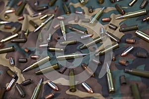 Many rifle bullets and cartridges on dark camouflage background