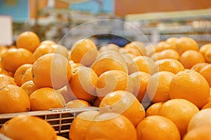 Many ripe oranges in plastic crates on market counter. Citrus fruit