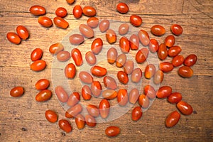 Many ripe red tomatoes lies on wooden surface