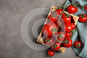 Many ripe red tomatoes in wooden crate on grey table, flat lay. Space for text