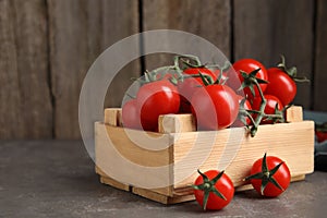 Many ripe red tomatoes in wooden crate on table. Space for text