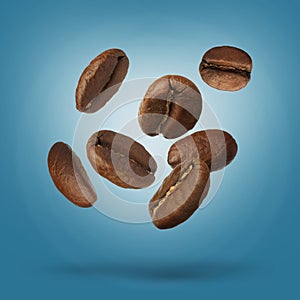 Many roasted coffee beans falling on light blue background