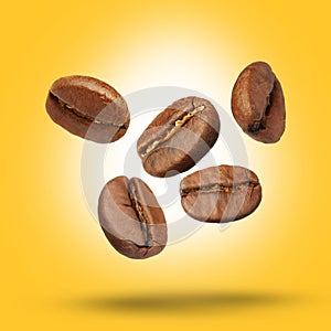 Many roasted coffee beans falling on yellow background
