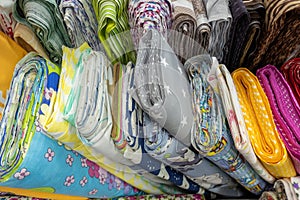 many rolls of colored fabric with different patterns