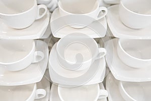 Many rows clean white coffee cup, tea spoon and saucer on table. Empty mug set in row prepare for coffee break