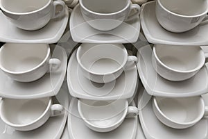 Many rows clean white coffee cup, tea spoon and saucer on table. Empty mug set in row prepare for coffee break