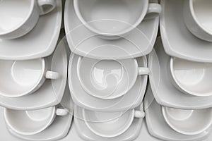 Many rows clean white coffee cup, tea spoon and saucer on table. Empty mug set in row prepare for coffee break