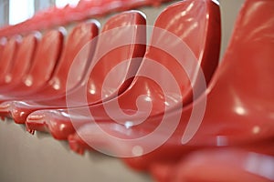 Many rows of red plastic seats in a grandstand stadium in the fresh air, day and light