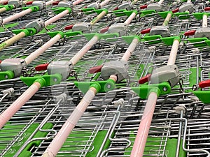 Many rows of shopping carts in the store close up with selective focus. The grocery shopping trolleys stacked. Lots of