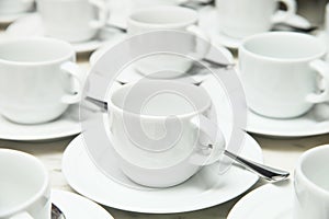 Many rows of white ceramic cup and saucer with teaspoon