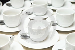 Many rows of white ceramic cup and saucer with teaspoon