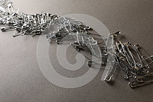 Many safety pins on light grey textured background