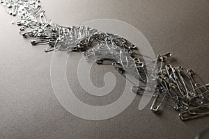 Many safety pins on light grey textured background