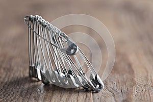 Many safety pins on wooden table, closeup. Space for text