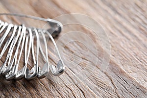 Many safety pins on wooden table, closeup. Space for text