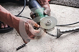 Many sharp sparks from motorcycle mechanic using old electric grinder with  motorcycle roller chain