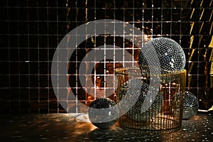 Many shiny disco balls on floor near foil party curtain. Space for text