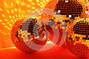 Many shiny disco balls near color wall, toned in orange