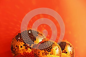 Many shiny disco balls near color wall, toned in orange. Space for text