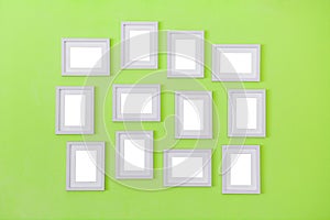 Many of simple white blank small picture frames hanging on green color wall background, copy space