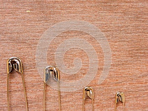 Many size of safety pin on wood background