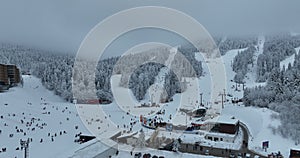 Many skiers and snowboarders skiing down on snowy mountainsides slopes in mountains at ski resort in winter. Family and