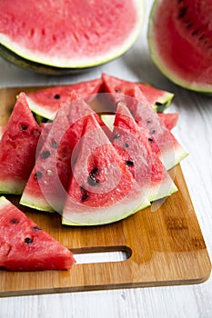 Many slices of ripe juicy watermelon on bamboo board, closeup. Side view.