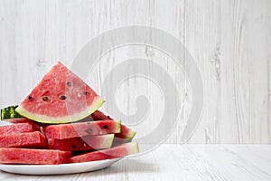 Many slices of ripe juicy watermelon on a round white plate with copy space, closeup.