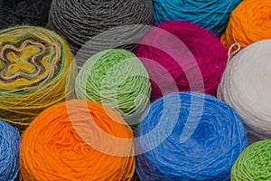 Many small balls of wool rainbowcolors on the wooden table.