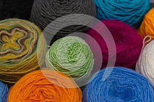 Many small balls of wool rainbowcolors on the wooden table.