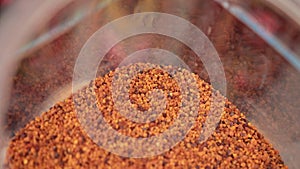 Many small different colors, orange, yellow, brown granules in plastic container