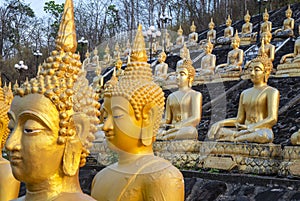 Many small,golden Buddha statues at Wat Phousalao,hilltop temple,reflecting sunset light,overlooking Mekong River,Pakse,southern