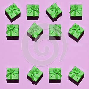 Many small green gift boxes on texture background of fashion trendy pastel pink color paper