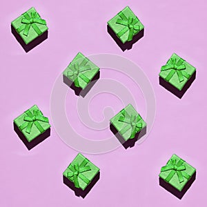 Many small green gift boxes on texture background of fashion trendy pastel pink color paper