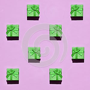 Many small green gift boxes on texture background of fashion trendy pastel pink color paper