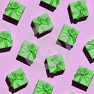 Many small green gift boxes on texture background of fashion trendy pastel pink color paper