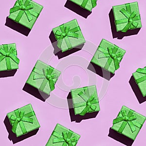 Many small green gift boxes on texture background of fashion trendy pastel pink color paper