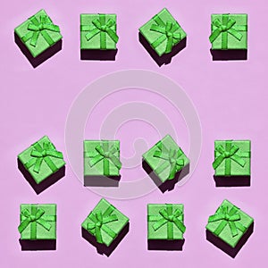 Many small green gift boxes on texture background of fashion trendy pastel pink color paper