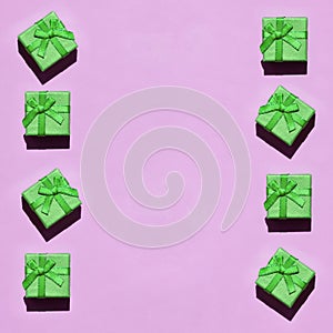 Many small green gift boxes on texture background of fashion trendy pastel pink color paper