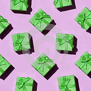 Many small green gift boxes on texture background of fashion trendy pastel pink color paper