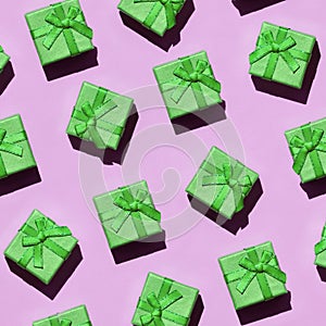 Many small green gift boxes on texture background of fashion trendy pastel pink color paper