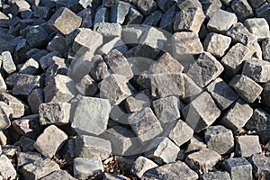 Many small paving stones in a pile, ready to be processed for cobblestone paving of a street. Close-up.