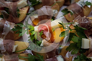 Many small peach and gorgonzola wrapped prosciutto snacks