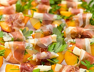 Many small peach and gorgonzola wrapped prosciutto snacks