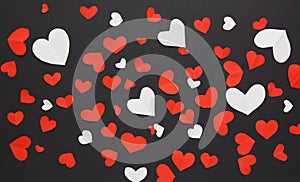 Many small red and white hearts on a black background. Background for decor