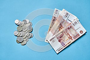 Many small Russian coins and five-thousand-dollar bills on a blue background, the concept of money