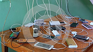 Many Smartphones and Mobile Phones Charging on the Table